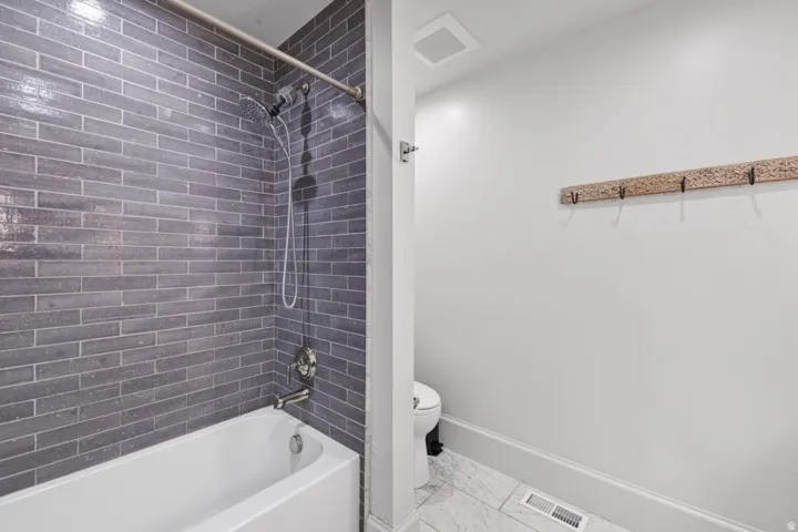 Bathtub with subway tile surround, brushed nickel fixtures, and a shower head with handheld sprayer