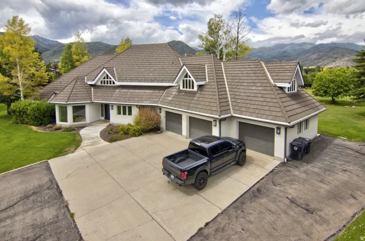 Expansive residence featuring a multi-gabled roofline, three garage doors, and a concrete driveway