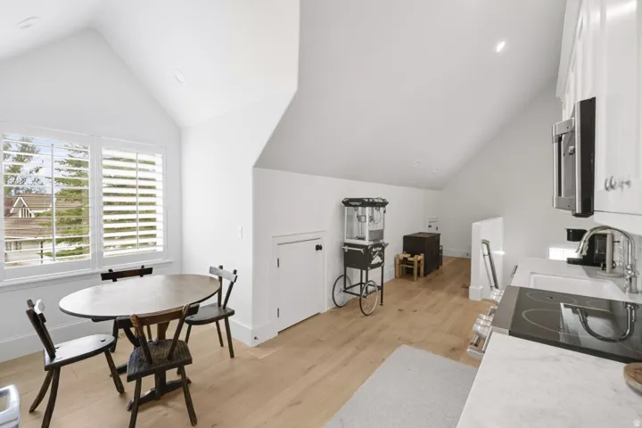 Angled ceilings, light wood-finish flooring, recessed lighting, and white plantation shutters