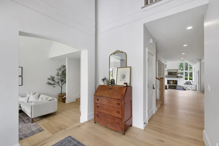 High ceilings, archway, wood-finish flooring, recessed lighting, and a stone-clad fireplace