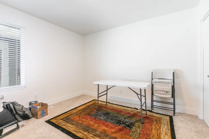 Carpeted room featuring a window with horizontal blinds and a white door