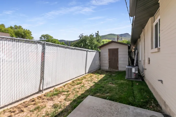 Chain link fencing with privacy slats, detached storage shed, exterior siding, and a window