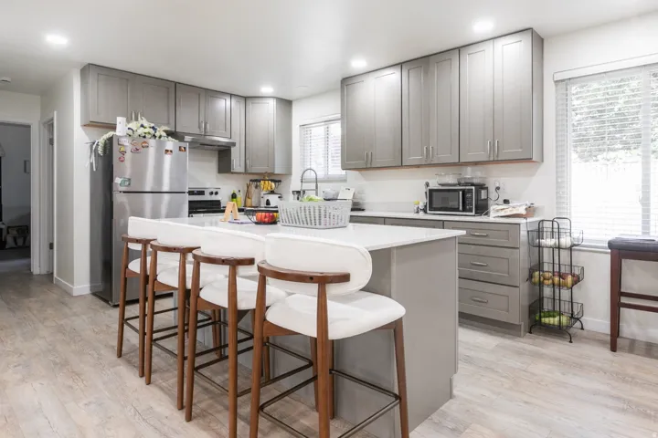 Kitchen featuring grey shaker-style cabinetry, stainless steel appliances, a center island with countertop seating, light-toned wood-finish flooring, and recessed lighting