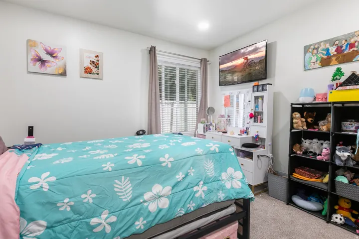 Recessed lighting illuminates this room featuring wall-to-wall carpeting and a window with blinds and drapes
