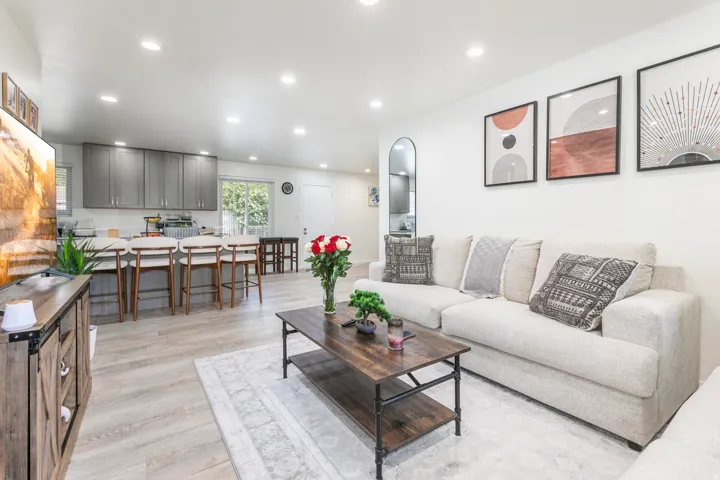 Open-concept living space with wood-finish flooring, recessed lighting, and a kitchen featuring gray cabinetry and a breakfast bar