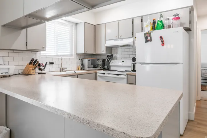 Kitchen featuring white appliances, subway tile backsplash, light-toned countertops, and recessed lighting