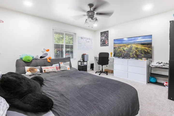Recessed lighting, ceiling fan with light fixture, window with blinds, light-toned carpeting.