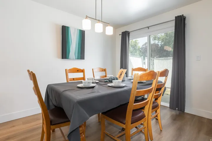 Dining area featuring wood-finish flooring, a contemporary linear chandelier, and a sliding glass door with exterior access