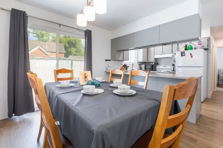 Sliding glass door, wood-finish flooring, recessed lighting, subway tile backsplash, and light gray cabinetry
