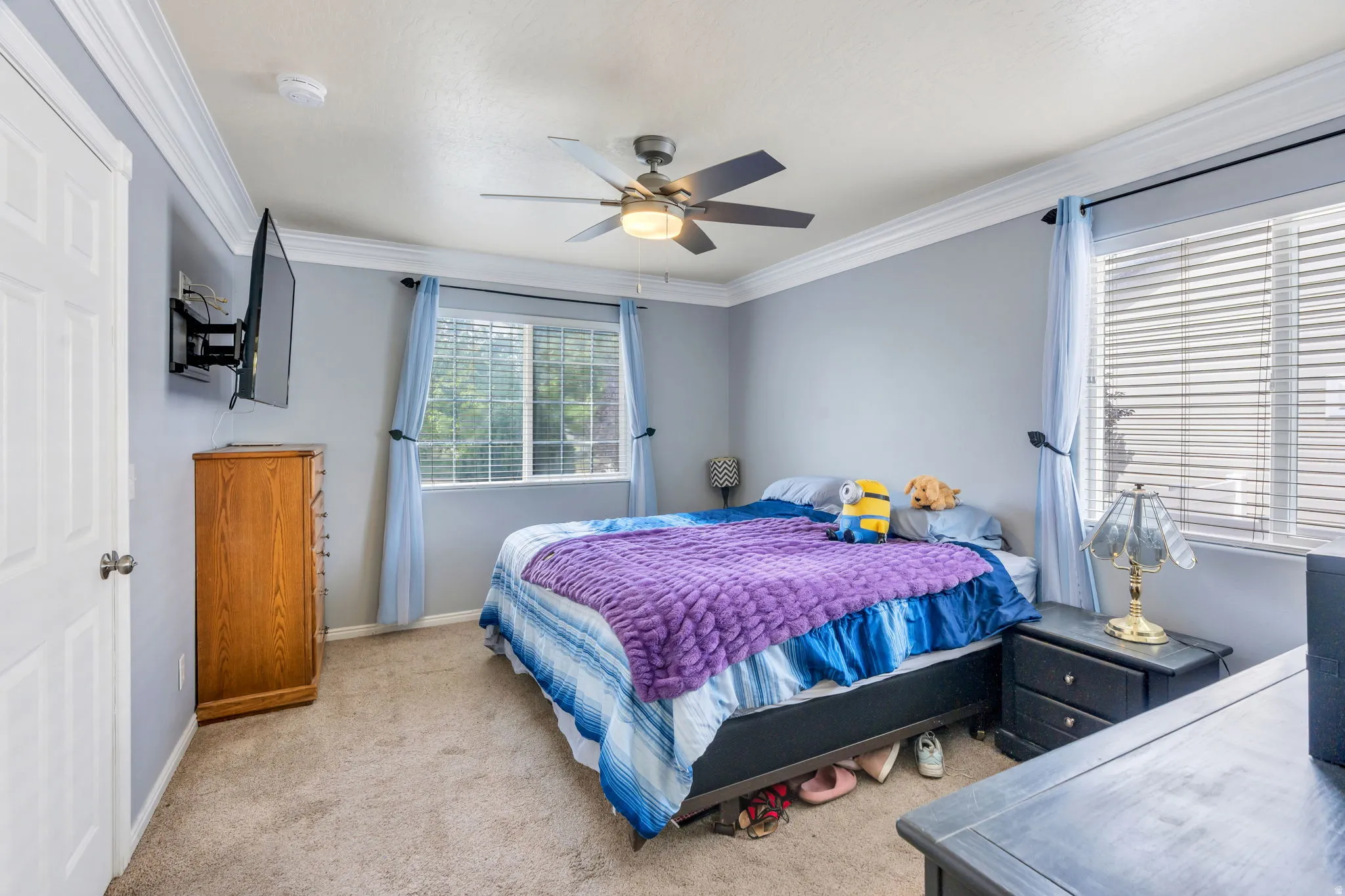 Neutral wall color with crown molding, ceiling fan with integrated lighting, and carpeted flooring