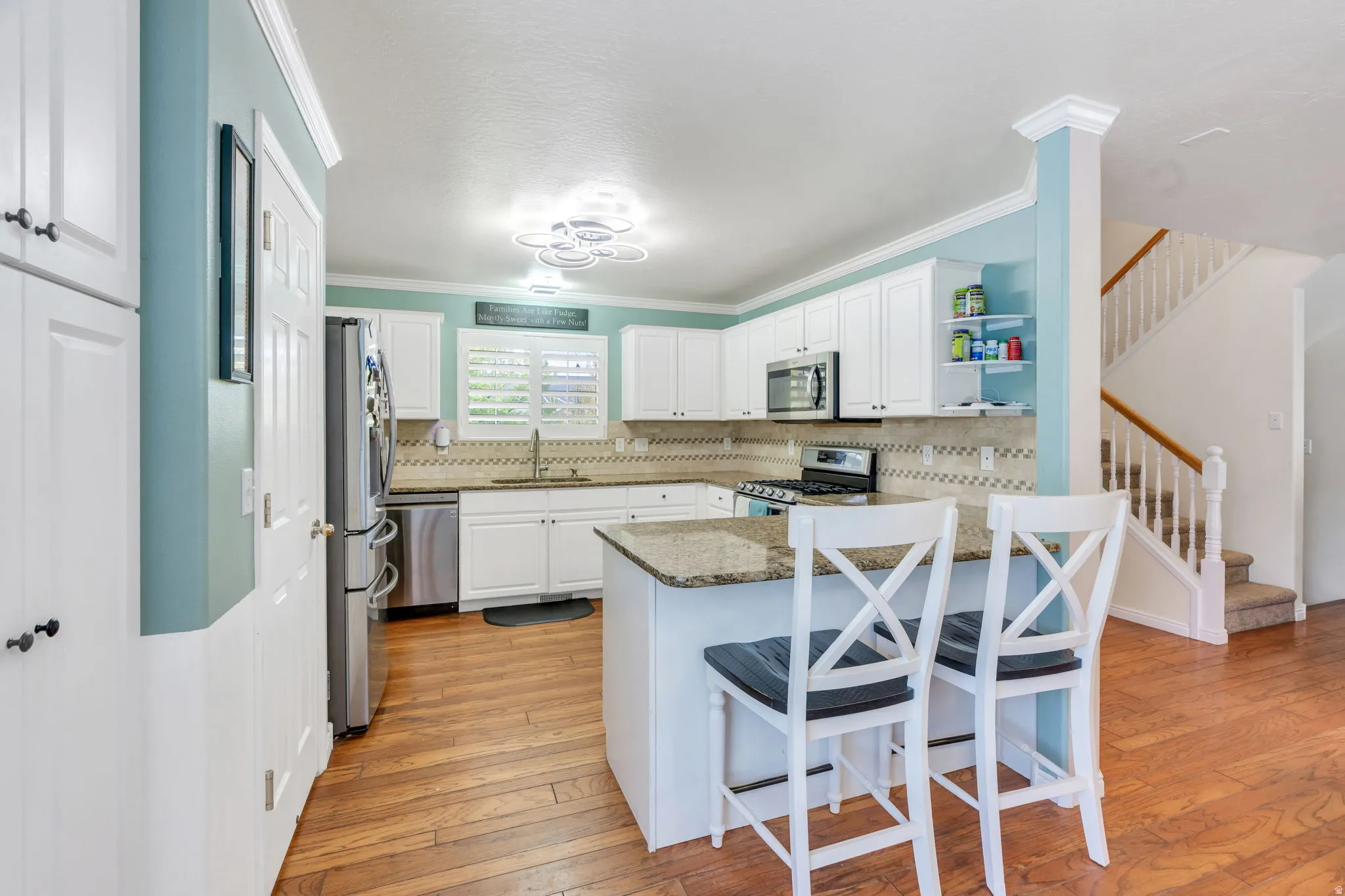 Kitchen featuring white cabinetry, stainless steel appliances, granite countertops, and wood-finish flooring