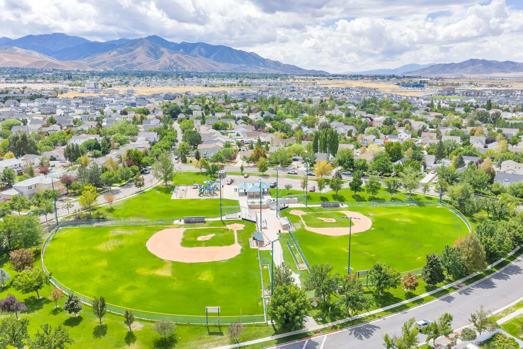 Community park featuring two baseball fields, a playground, and mature trees