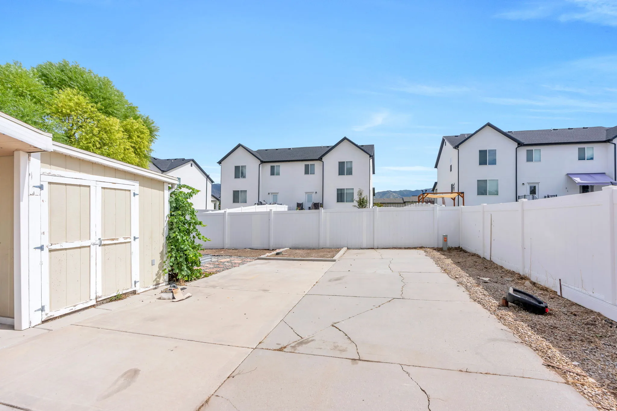 Fenced backyard featuring a concrete patio, detached storage shed, and gravel landscaping