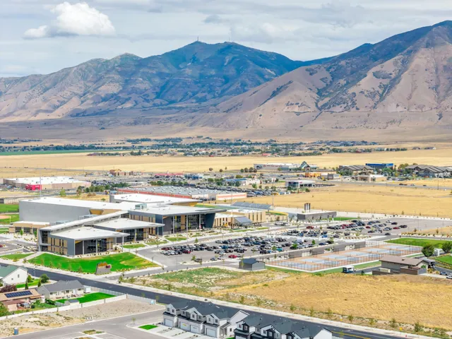 Expansive mountain backdrop with a substantial commercial development, multiple parking areas, and residential structures in the foreground
