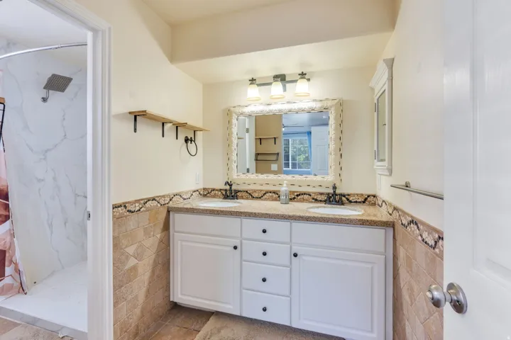 Dual vanity with white cabinetry, a light-toned countertop, and decorative tile backsplash