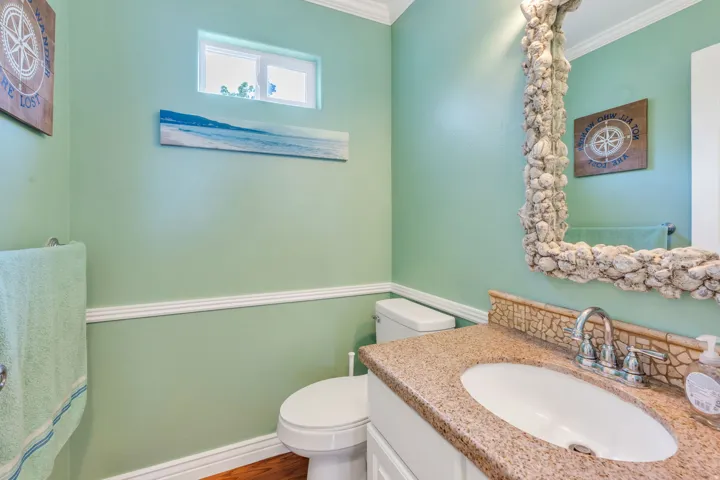 Powder room featuring a white single vanity, granite-finish countertop, and wood-finish flooring