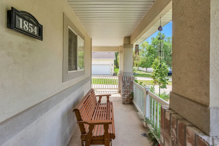 Covered porch featuring stucco siding with a brick veneer accent, a textured concrete floor, and a white railing