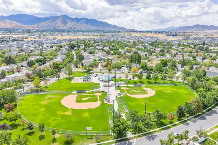 Community park featuring two baseball fields, a playground, and mature trees