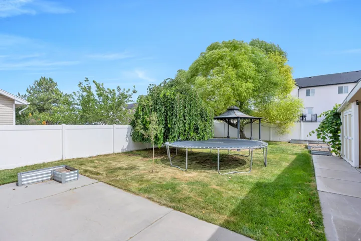Expansive backyard featuring a white privacy fence, concrete patio, and a gazebo with a dark roof