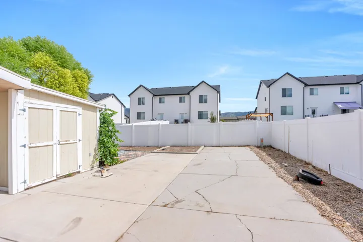 Fenced backyard featuring a concrete patio, detached storage shed, and gravel landscaping