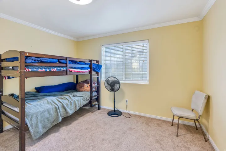 Recessed window with horizontal blinds, carpeted flooring, and crown molding