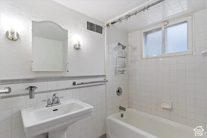 Pedestal sink with chrome faucet, wall-mounted mirror, and vanity lighting