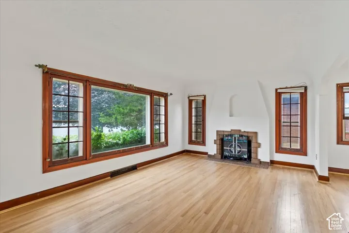 Hardwood flooring, a prominent fireplace with tile surround, a large picture window, and additional windows with wood trim