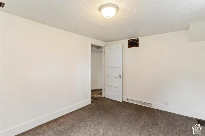 Carpeted flooring, white paneled door, and ceiling-mounted light fixture