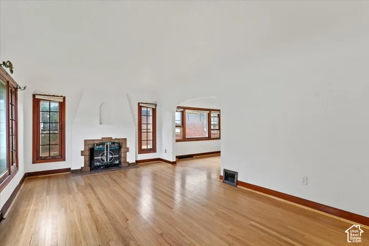 Hardwood flooring throughout, arched fireplace with tile surround, wood-framed windows, and a coved ceiling
