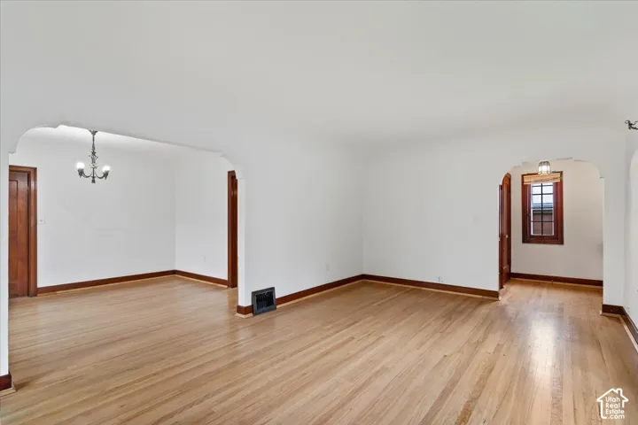 Hardwood flooring, arched doorways, classic chandelier, and dark wood trim