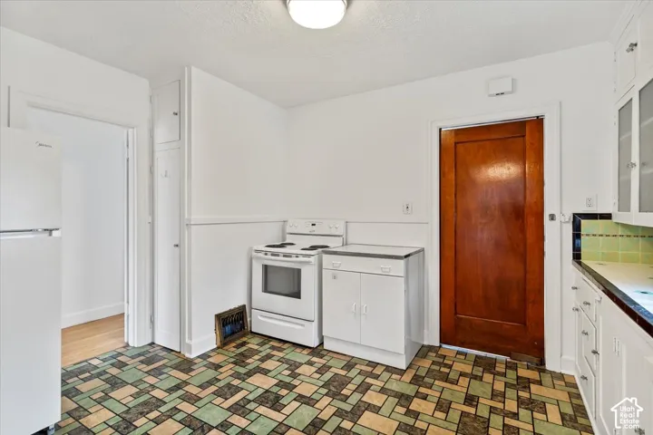 Kitchen featuring patterned flooring, white cabinetry, integrated range, and a wood-finish door