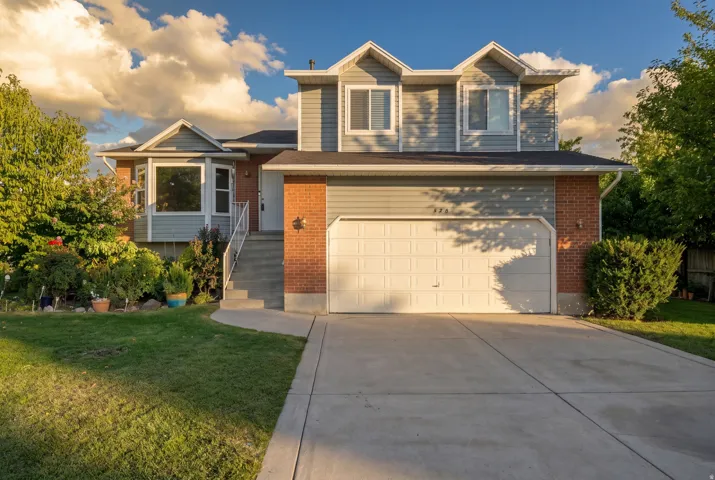 Two-story residence featuring a two-car garage, brick and siding exterior, concrete driveway, and a manicured lawn