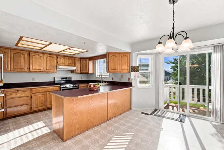 Kitchen with wood cabinetry, dark countertops, and a central island