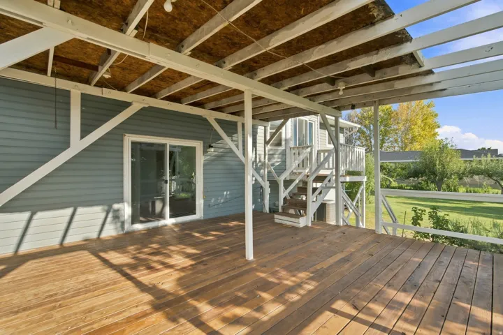 Covered wood deck with exposed rafter ceiling, wood siding, and sliding glass door