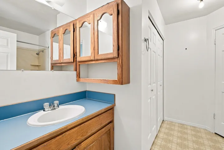 Vanity with a blue countertop, an oval undermount sink, and wood-finish cabinetry