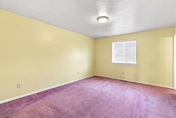 Recessed window with horizontal blinds, overhead flush mount light fixture, textured ceiling, and carpeted flooring