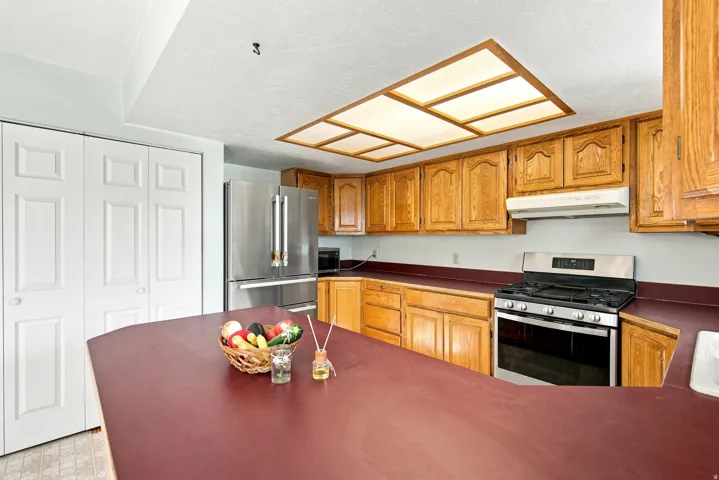 Galley-style kitchen with wood-finish cabinetry and dark countertops
