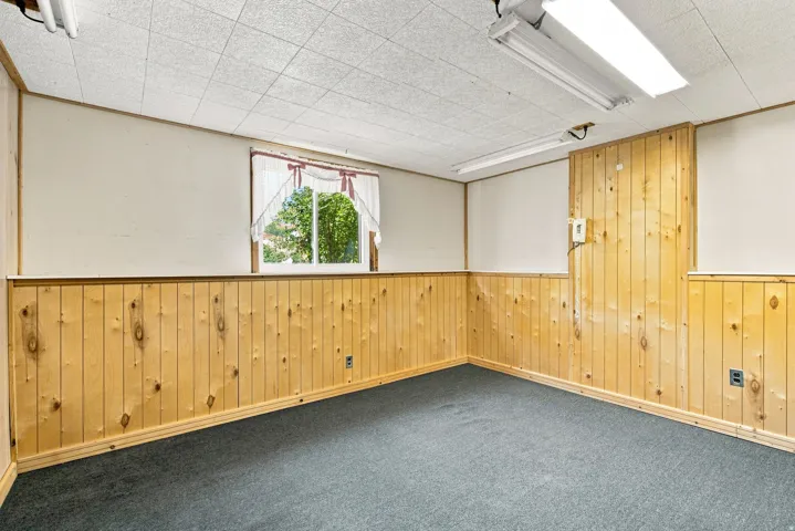 Recessed window, wood paneling, drop ceiling, and carpeted flooring