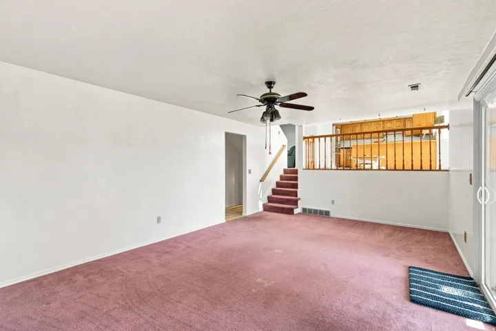 Interior space featuring a ceiling fan, sliding glass door, and a staircase with wooden railing