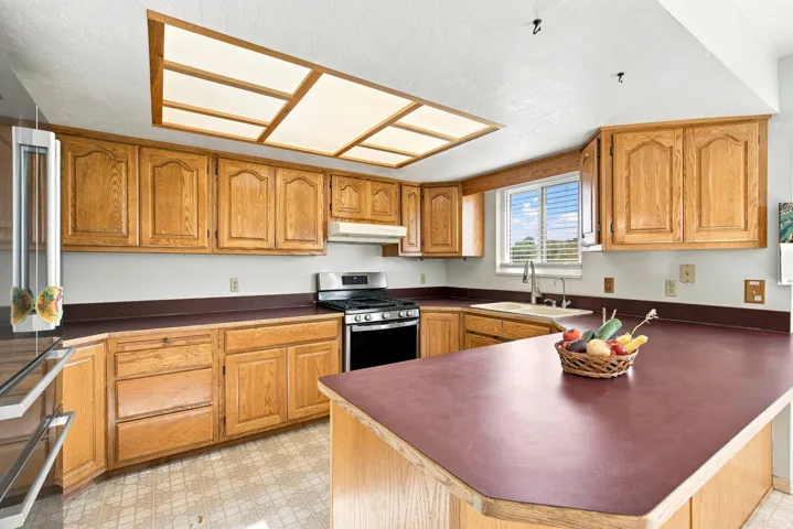 Kitchen featuring wood cabinetry, integrated gas range, and a dual-basin sink with a gooseneck faucet