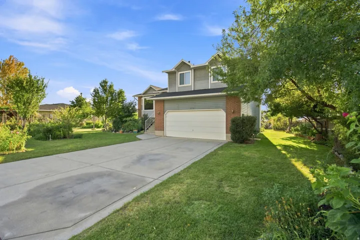 Two-story home featuring a two-car garage, concrete driveway, brick accents, and mature landscaping