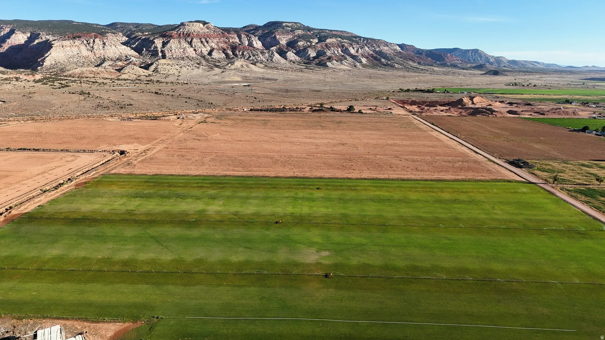 Expansive, cultivated land featuring green fields and arid terrain