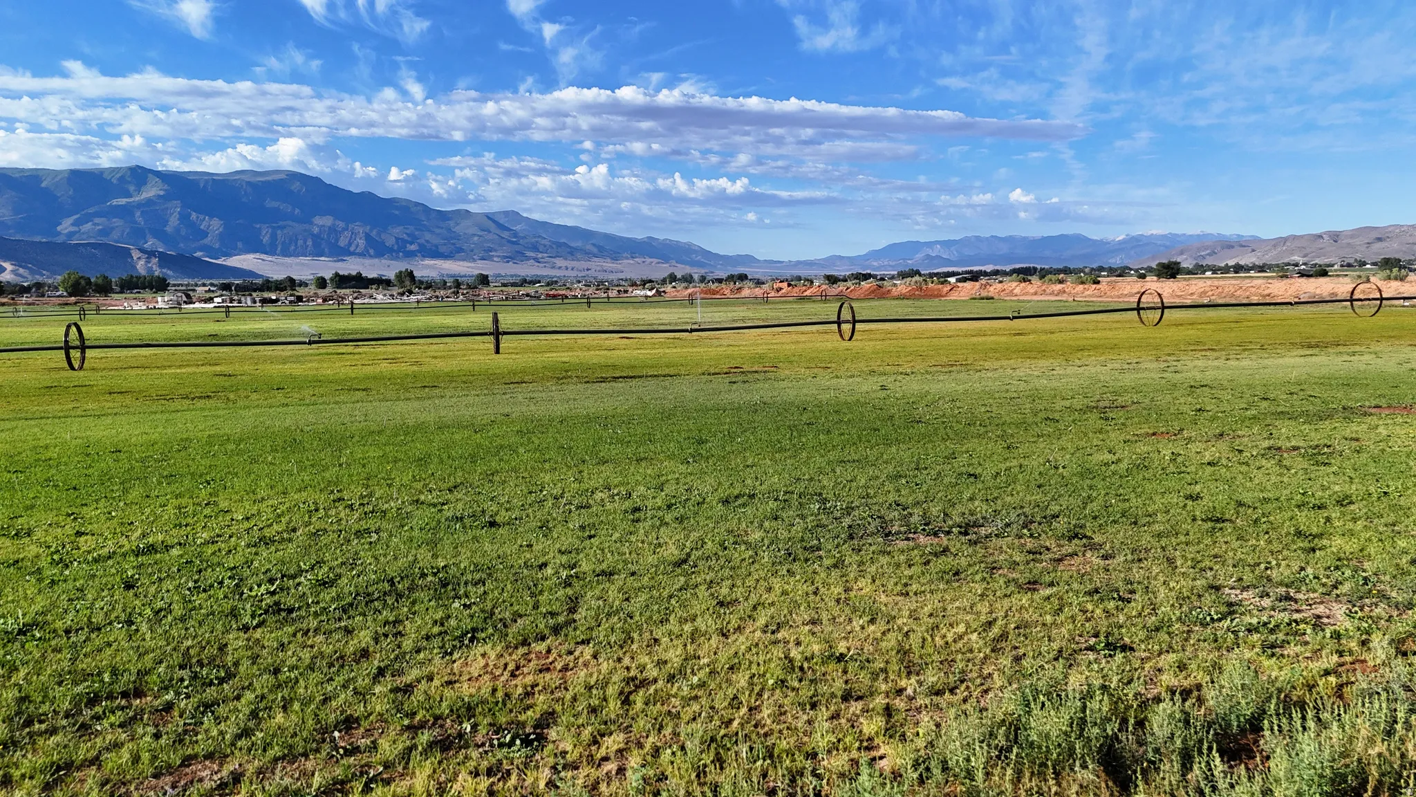 Expansive green landscape with a distant mountain range and clear skies