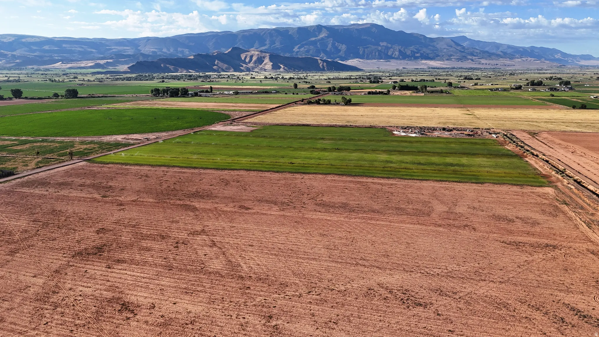 Expansive rural landscape featuring cultivated fields and distant mountain ranges
