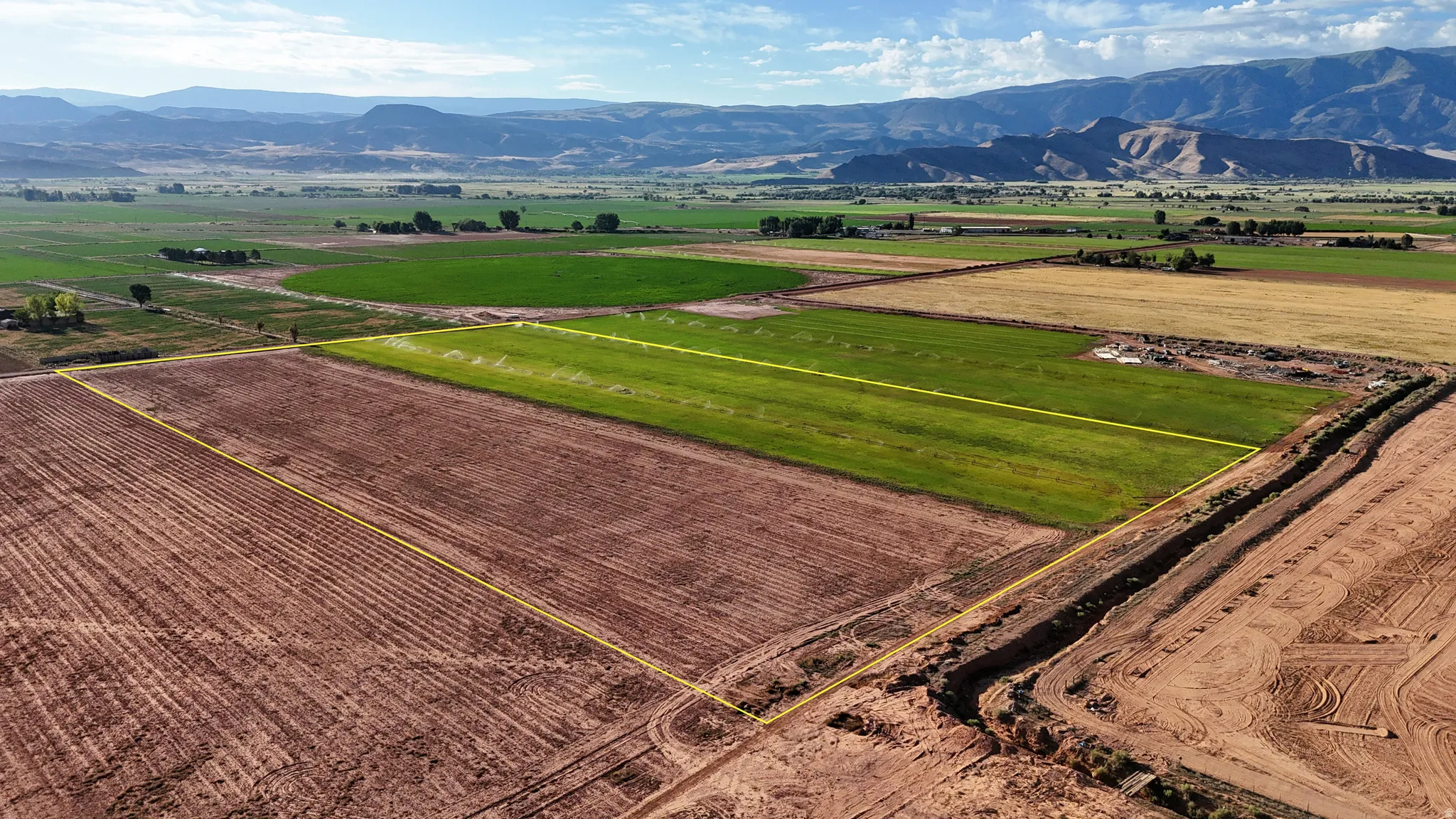 Expansive agricultural land featuring a cultivated field and a partially tilled area