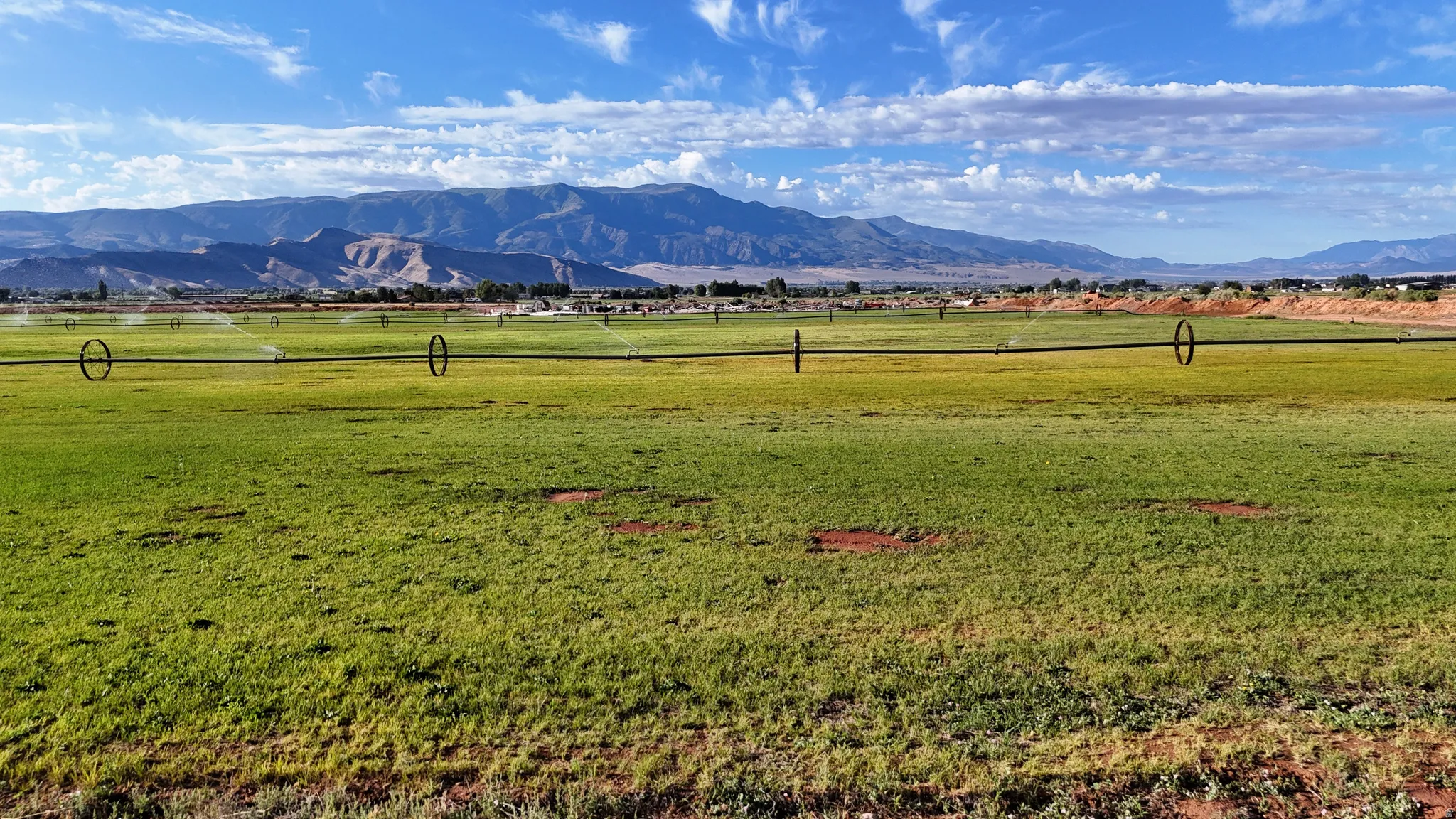 Expansive green field with an installed irrigation system and distant mountain range