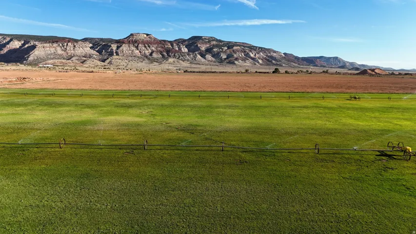 Expansive green fields with irrigation systems, complemented by distant mountains and a clear sky