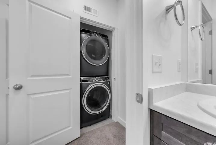 Built-in stacked washer and dryer, vanity with integrated sink, and wall-mounted mirror