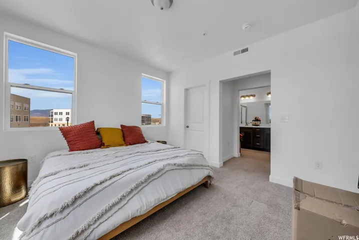 Bright bedroom with two windows and neutral carpeting