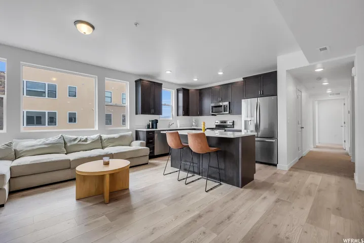 Open-concept living space with light wood-finish flooring, recessed lighting, and large windows
